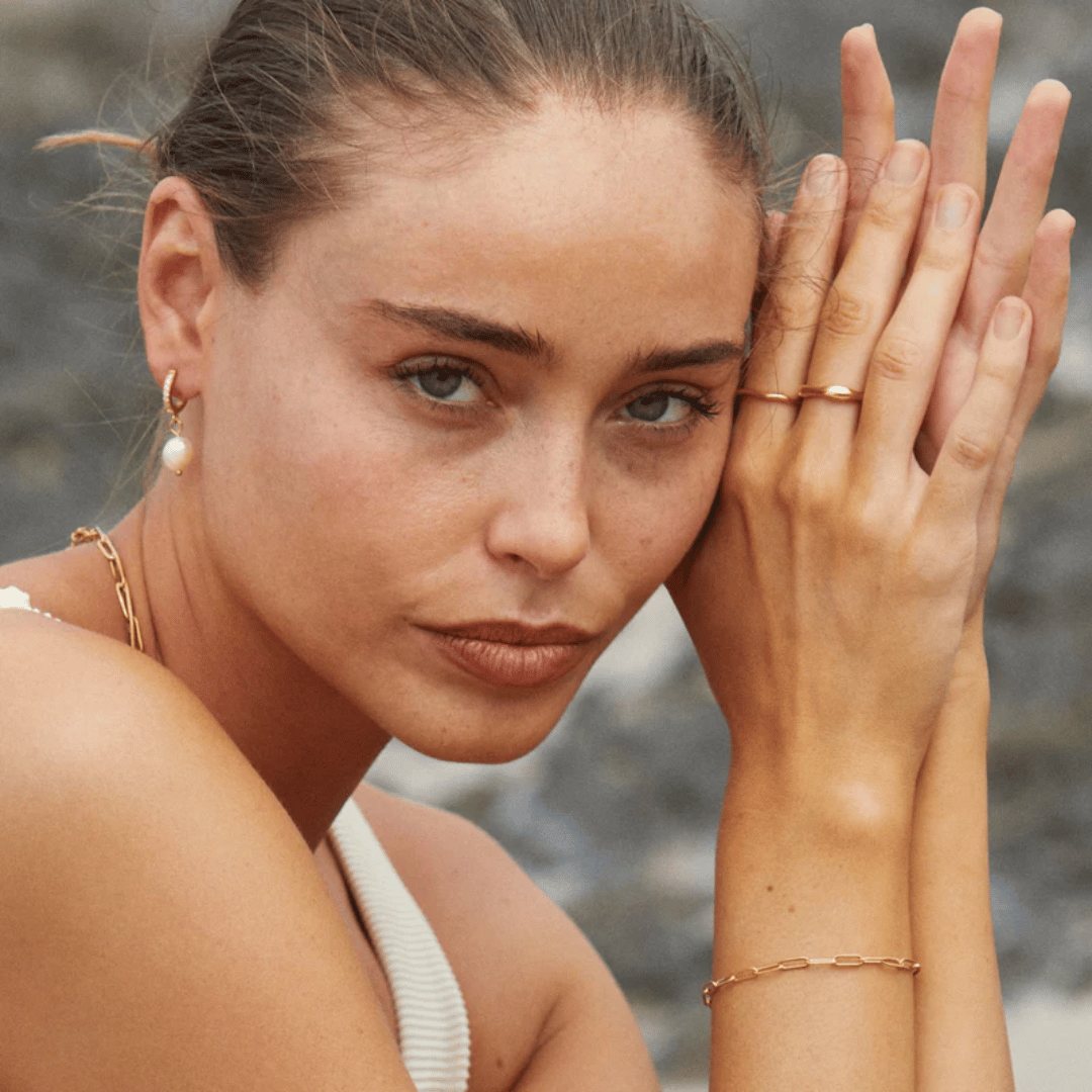 Model posing with arms up wearing Moonela zodiac rings – Moonela astrology-inspired jewelry
